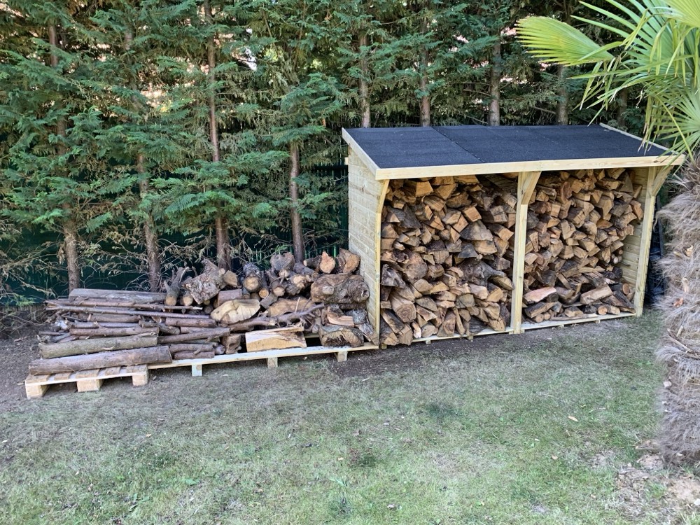 Abri à bûches en bois construit au fond d'un jardin